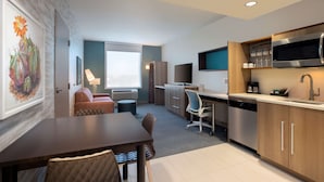 A modern hotel room with a dining area, kitchenette, and a large window. - Home2 Suites by Hilton Phoenix Avondale (Avondale)