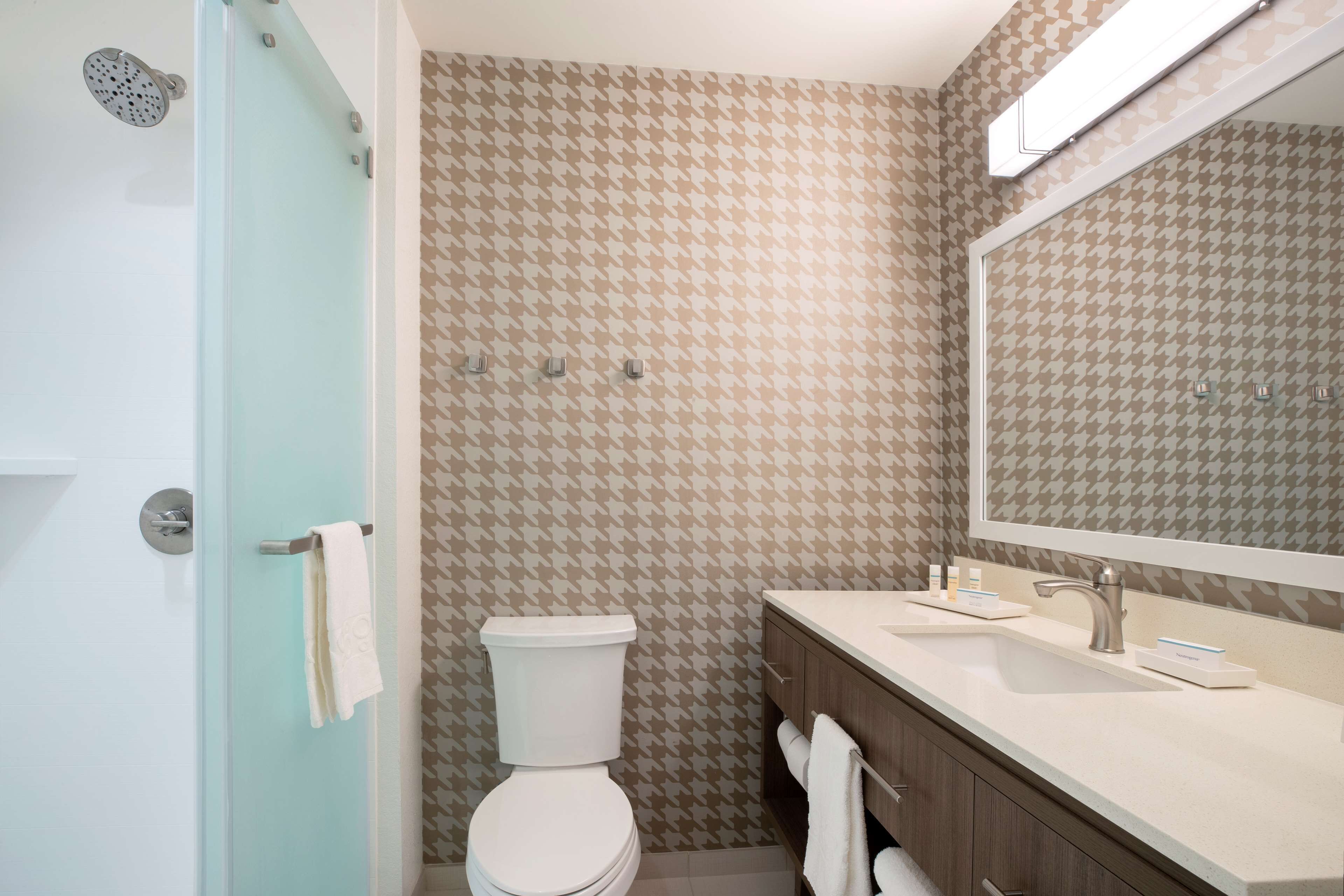 A bathroom with a toilet, sink, and mirror.