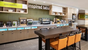 A modern restaurant with a breakfast bar, a sign reading "GOOD MORNING", and a counter with various food items. - Home2 Suites by Hilton Phoenix Avondale (Avondale)
