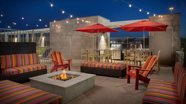 An outdoor patio with seating, a fire pit, and string lights. - Home2 Suites by Hilton Phoenix Avondale (Avondale)