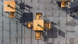 A top-down view of a terrace with wooden tables and chairs, arranged in a square pattern. - Hampton by Hilton York Piccadilly (York)