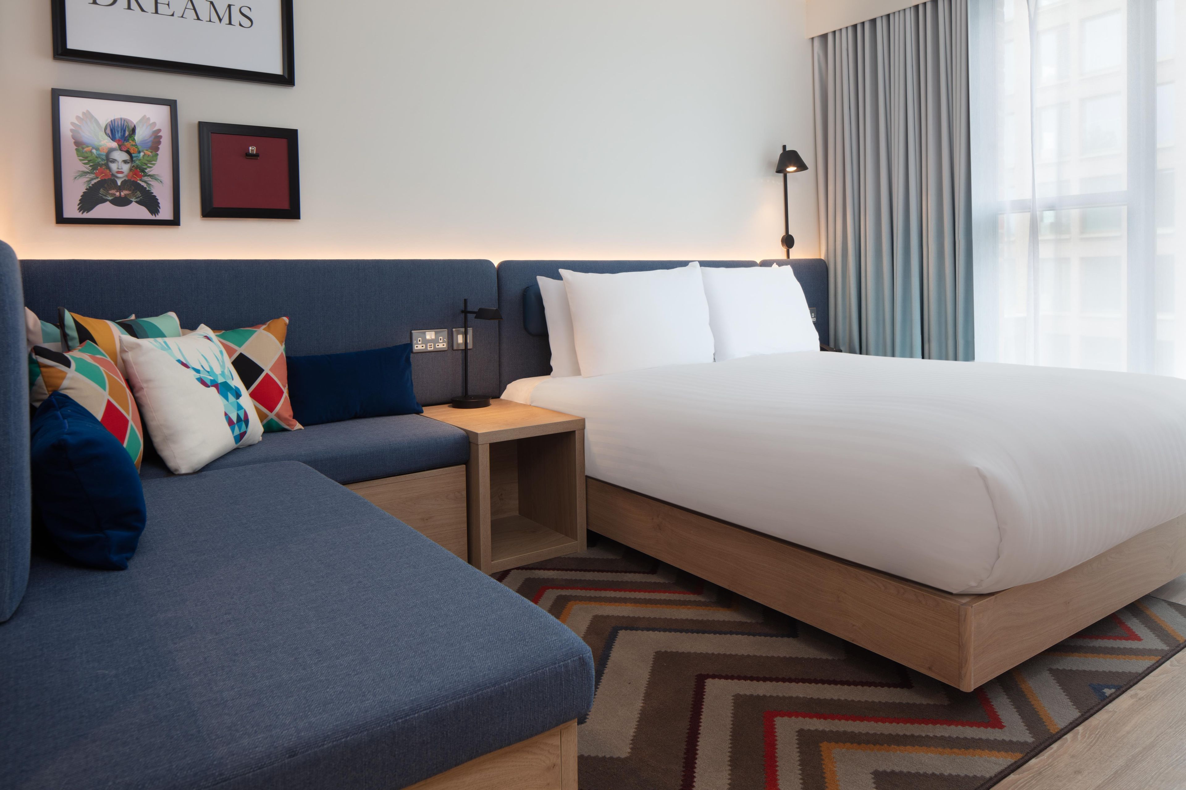 Une chambre d’hôtel avec un grand lit, un canapé, une table de chevet et un mur orné de tableaux.