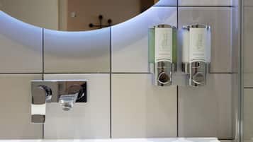 A bathroom with a modern design, featuring a large mirror, a chrome faucet, and two hand soap dispensers labeled 'Therapy Water Therapy'.