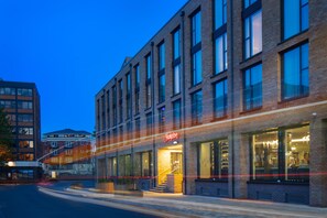 A multi-story building with a prominent 'Hampton' sign, large windows, and a visible staircase leading to the entrance. - Hampton by Hilton York Piccadilly (York)