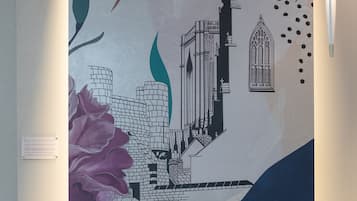 A wall with a large abstract mural featuring architectural elements and floral designs.