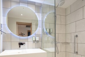 A modern bathroom with a large mirror, a shower, and a sink. - Hampton by Hilton York Piccadilly (York)