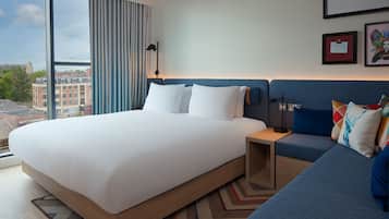 Una habitación de hotel moderna con una cama grande, un sofá y vistas a la ciudad.