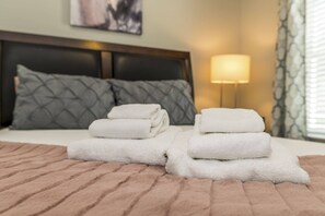 A neatly made bed with a pink quilt, two pillows, and a stack of white towels. - Roomy Town Home, Mickey-themed Bedroom! #4bv550 (Kissimmee)