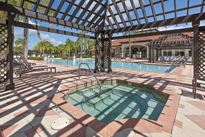 A pool area with a hot tub, sun loungers, and a pergola structure. - Roomy Town Home, Mickey-themed Bedroom! #4bv550 (Kissimmee)