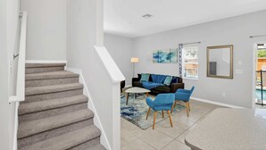 Eine Treppe führt zu einem Wohnbereich mit einer Couch, einem Couchtisch und Sesseln.
