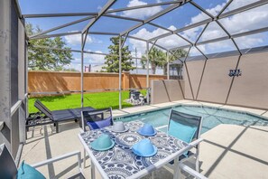 A covered outdoor area with a pool, lounge chairs, and a table with decorative hats. - Roomy Town Home, Mickey-themed Bedroom! #4bv550 (Kissimmee)