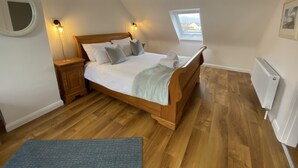 Un dormitorio con cama de madera, dos lámparas de noche, un tragaluz pequeño y un radiador.