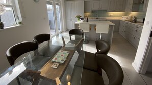 Una cocina moderna con armarios blancos, una isla central con taburetes y una mesa de comedor con sillas.