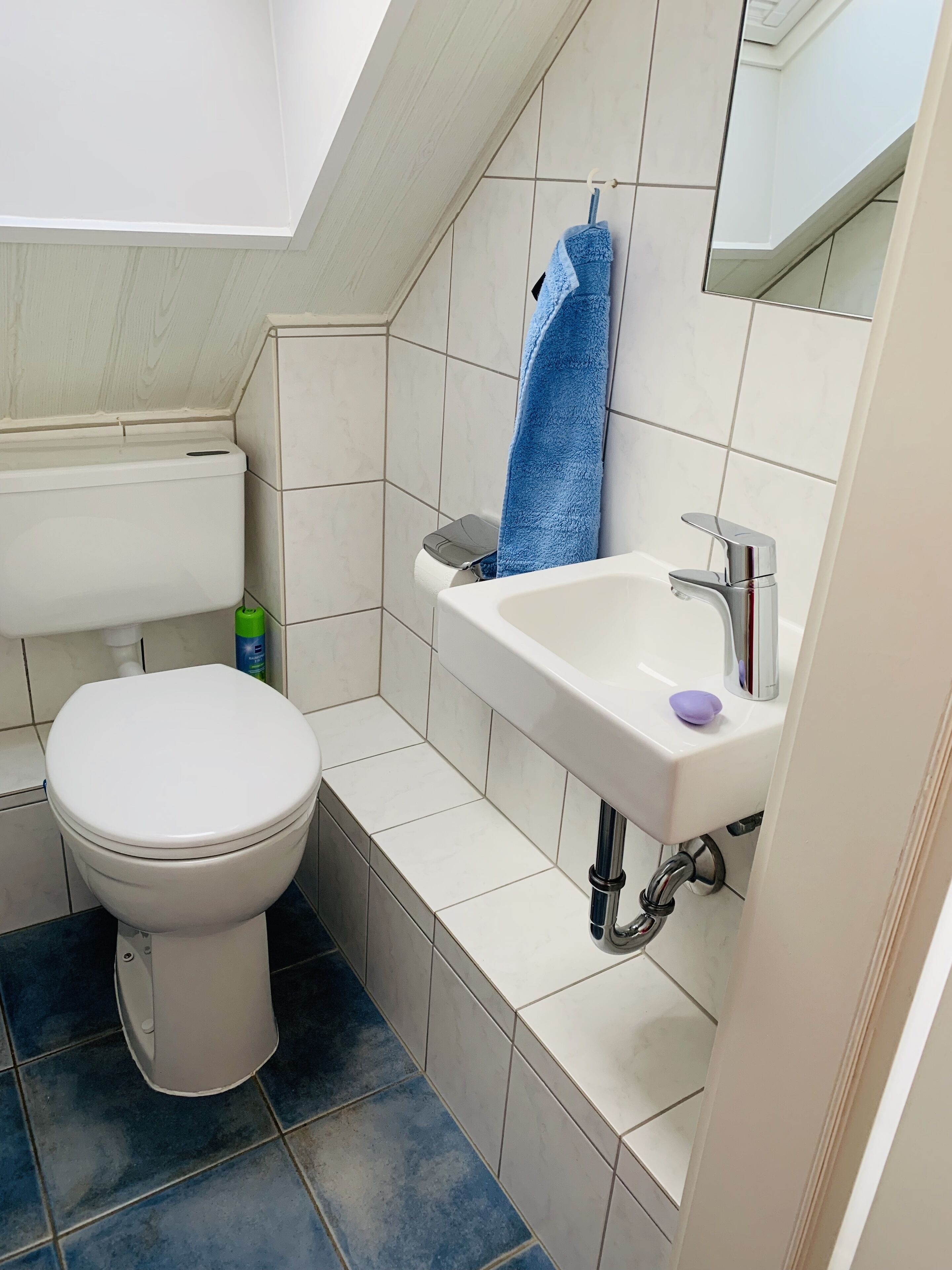 A bathroom with a toilet, sink, and mirror.