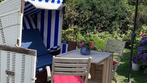Een gezellig buitenzitgedeelte met een gestreepte strandstoel, een houten tafel en een bijpassende parasol.