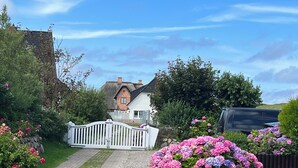 Een charmant huis met een witte picket fence, een pad van stenen en levendige roze en paarse bloemen.