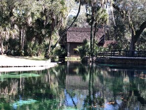 A calm water body surrounded by trees and a wooden building.