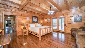 L’intérieur d’un chalet en bois, avec un lit en bois, un ventilateur de plafond et un coin repas.