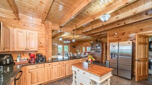 Une cuisine spacieuse dotée de meubles en bois, d’un îlot central, d’appareils électroménagers en acier inoxydable et offrant une vue sur l’extérieur.