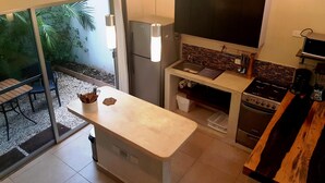 Een kleine keuken met een inbouwfornuis, een spoelbak en een grote televisie.