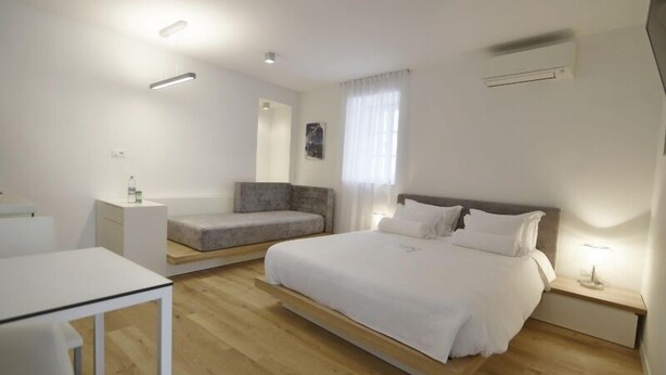 Une chambre moderne avec un grand lit, un petit canapé, une table de chevet et un bureau.