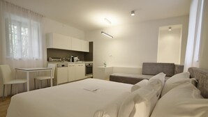 Une chambre d’hôtel moderne dotée d’un grand lit, d’une petite kitchenette, d’un coin repas et d’un espace salon séparé.