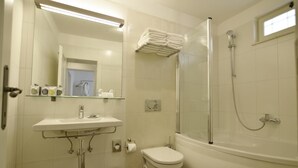 Une salle de bain moderne avec une douche à parois de verre, un lavabo blanc et des toilettes.