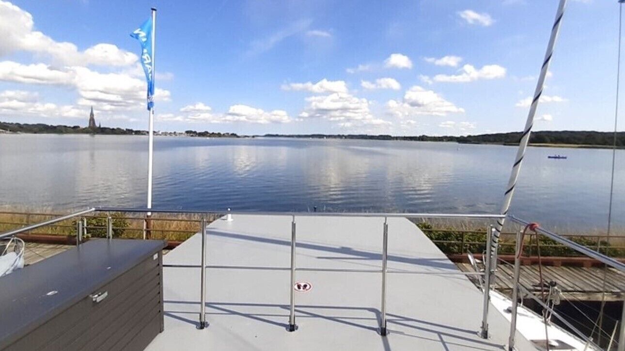 Un lago tranquilo con cielo despejado, una bandera y un muelle.