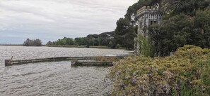 Una torre de piedra histórica junto a un lago, rodeada de follaje.
