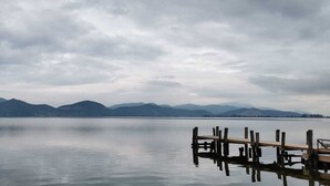 Un lago tranquilo con montañas al fondo y un muelle de madera que se adentra en el agua.
