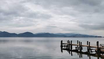 A calm lake with mountains in the background and a wooden dock extending into the water.
