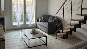 A modern living room with a sofa, a coffee table, and a staircase. - Comfortable house, seaside + Private Parking (Gruissan)