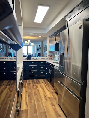 Una cocina moderna con armarios oscuros, electrodomésticos de acero inoxidable y piso de madera.