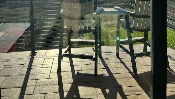 Eine Terrasse mit Tisch und Stühlen mit Blick auf einen Strand.