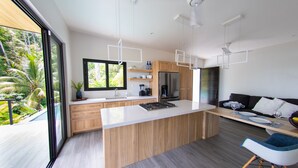 Une cuisine moderne dotée d’un grand îlot central, de meubles en bois et offrant une vue sur un jardin luxuriant.