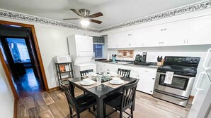 Una cocina moderna con gabinetes blancos, encimera negra y horno de acero inoxidable.