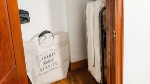 Una sala de lavandería con piso de madera, pared blanca y un tendedero. Se ve una bolsa blanca con texto en el suelo.