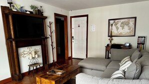 Una sala de estar con chimenea, un sofá gris, una mesa de centro de madera y una estantería.