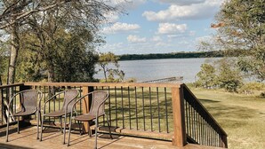 A wooden deck with outdoor furniture, overlooking a lake with a clear sky.