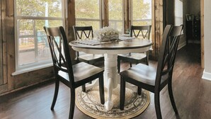A dining area with a round table, four chairs, and a decorative rug.
