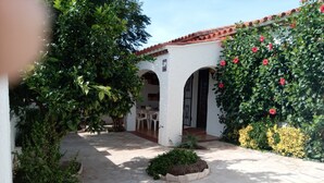A courtyard with stone flooring, a white building with arches, and lush greenery including flowering plants. - Nice and relax Mediterranean villa with free wifi  (Miami Playa)