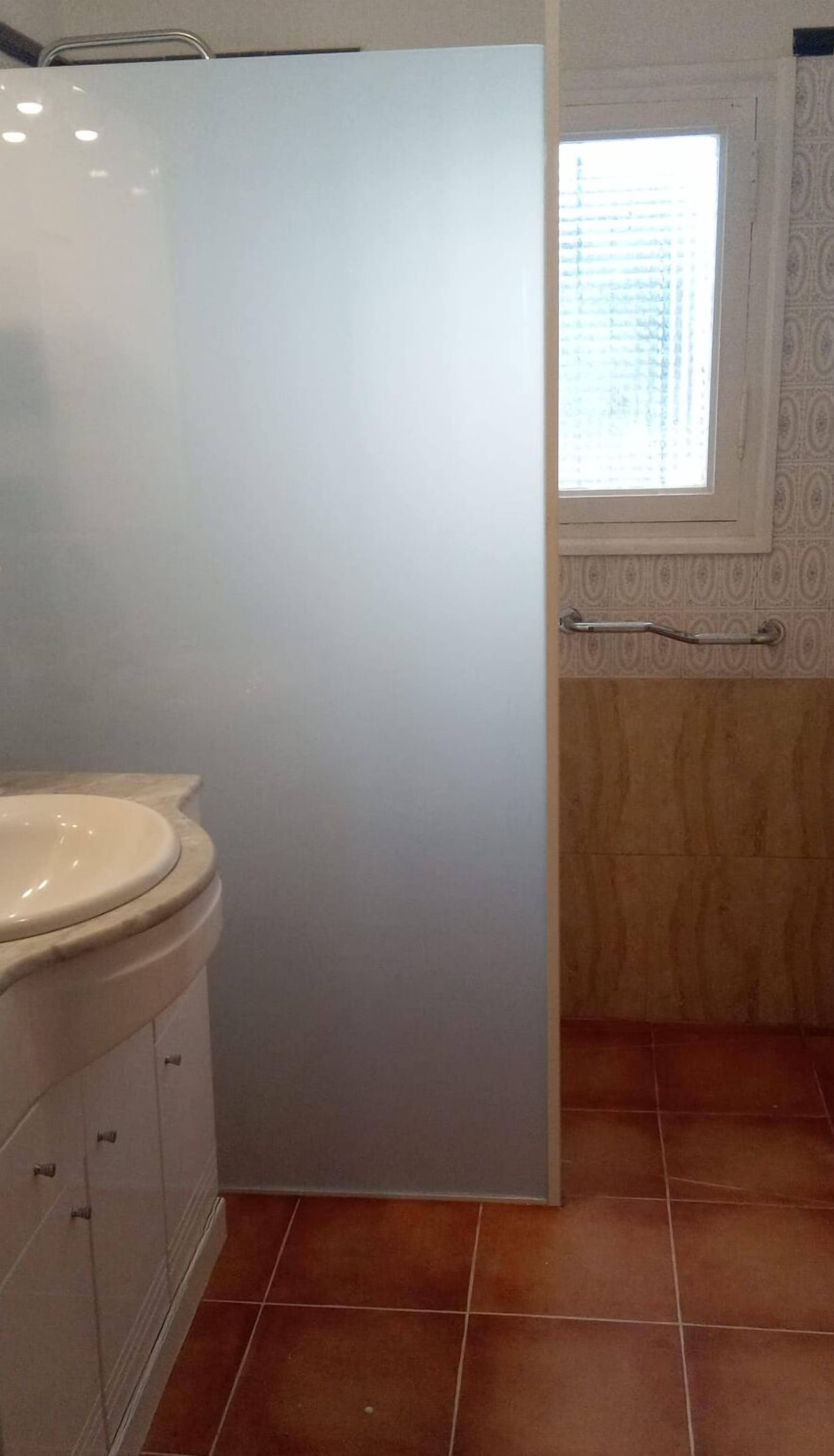 Ett badrum med en vit toalett, ett handfat och ett fönster med persienner.