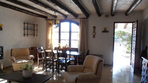A spacious living room with a fireplace, a dining area with a table and chairs, and a large window allowing natural light. - Nice and relax Mediterranean villa with free wifi  (Miami Playa)