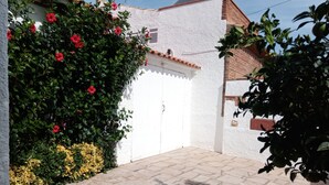 A courtyard with a white wall, a tiled roof, and a paved area. - Nice and relax Mediterranean villa with free wifi  (Miami Playa)
