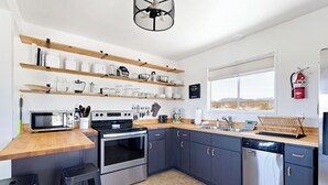 Een moderne keuken met houten planken, roestvrijstalen apparatuur en een groot raam.