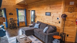 Un intérieur chaleureux de chalet en bois, avec un canapé d’angle, une table basse en bois et un coin repas.
