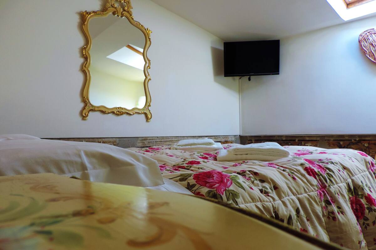 A hotel room with a bed, a television mounted on the wall, and a decorative mirror.
