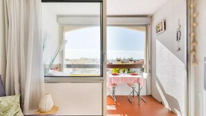 Quarto com porta de vidro deslizante que dá para uma varanda externa com mesa posta para refeições.