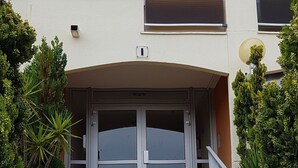 Um edifício com entrada central, escadaria que a leva e uma grande janela acima da entrada.