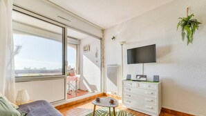 Uma sala de estar moderna com um sofá, uma mesa de centro, uma televisão e uma varanda com vista.